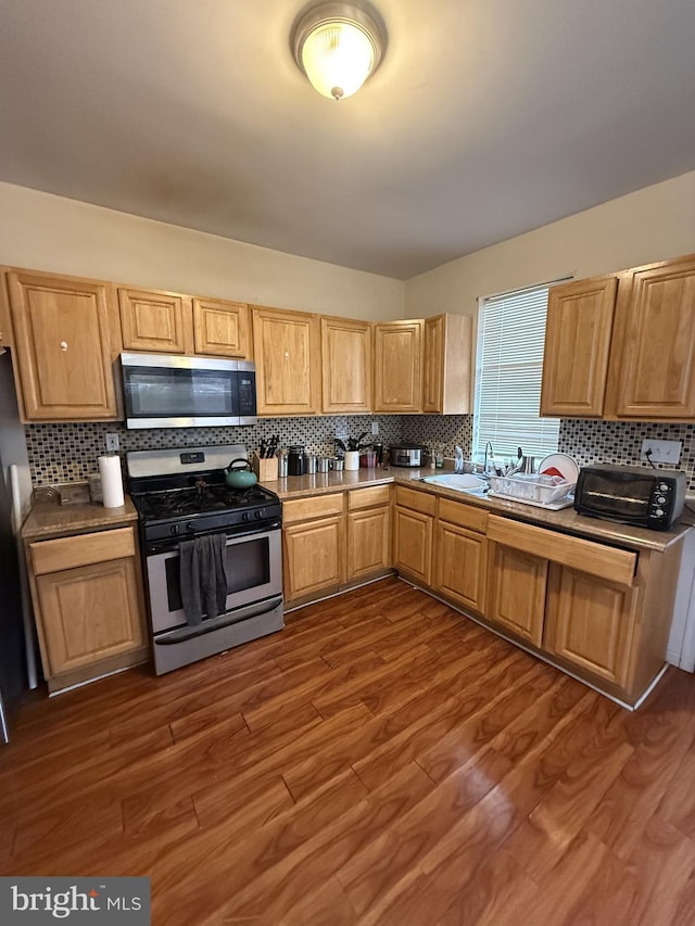 kitchen featuring tasteful backsplash, appliances with stainless steel finishes, dark hardwood / wood-style floors, and sink