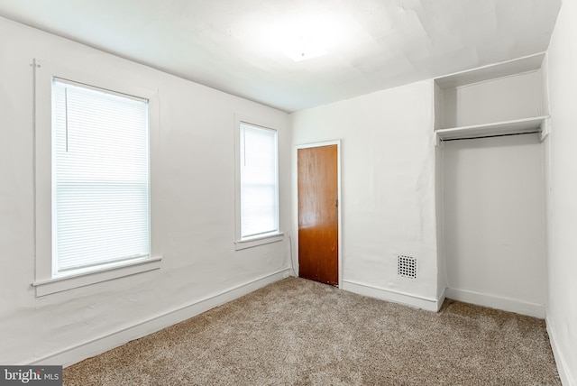 unfurnished bedroom featuring light carpet and a closet