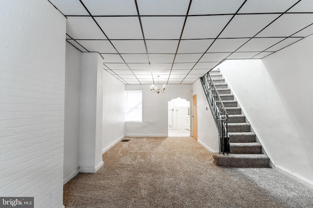 basement with an inviting chandelier, a paneled ceiling, and carpet