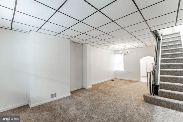 basement with an inviting chandelier, a paneled ceiling, and carpet