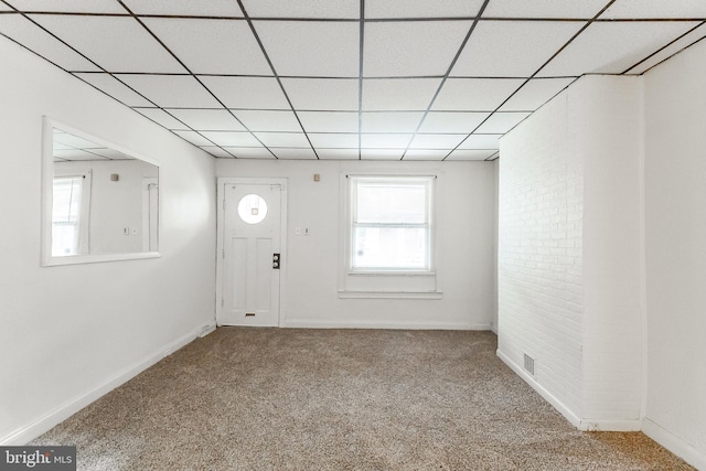 foyer entrance featuring brick wall, carpet floors, and a drop ceiling