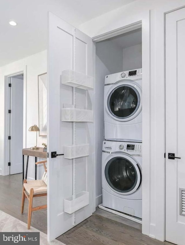 laundry area with dark wood-type flooring and stacked washing maching and dryer