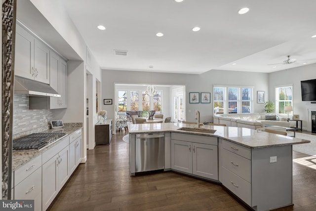 kitchen featuring sink, stainless steel appliances, light stone counters, and decorative light fixtures