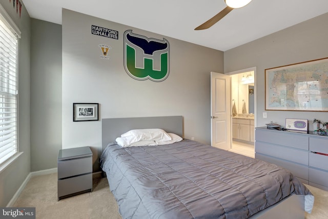 bedroom featuring light carpet, ensuite bathroom, and ceiling fan