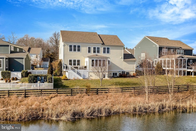 back of property with a yard and a water view