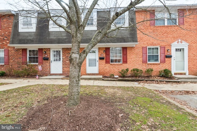 townhome / multi-family property featuring a shingled roof and brick siding