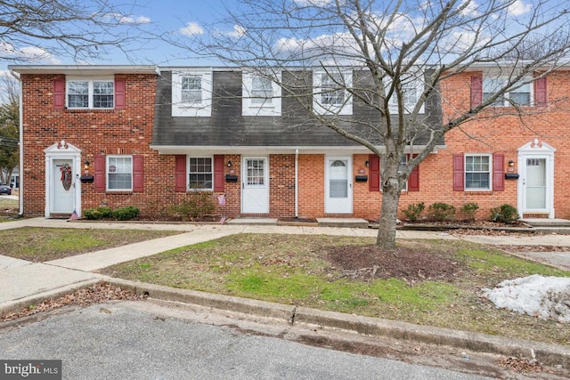 townhome / multi-family property featuring a shingled roof and brick siding