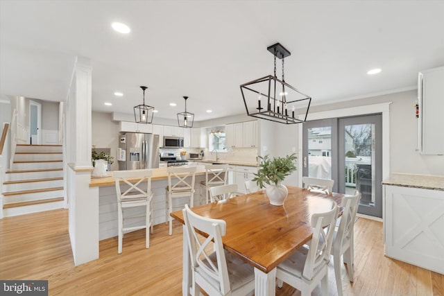 dining area with sink, crown molding, light hardwood / wood-style floors, and a healthy amount of sunlight