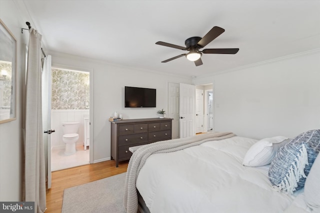 bedroom featuring crown molding, ceiling fan, light hardwood / wood-style floors, and ensuite bath