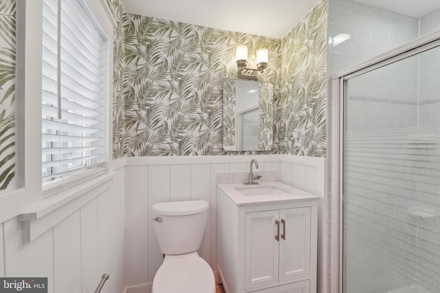 bathroom featuring vanity, toilet, and a shower with shower door