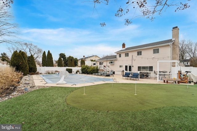 back of property featuring a covered pool and a patio area