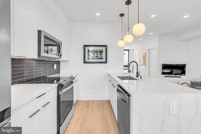 kitchen featuring sink, white cabinetry, pendant lighting, stainless steel appliances, and light stone countertops