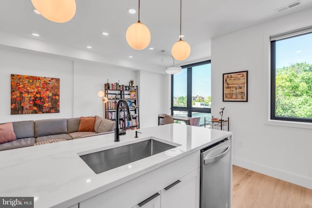 kitchen featuring sink, white cabinetry, decorative light fixtures, dishwasher, and light stone countertops