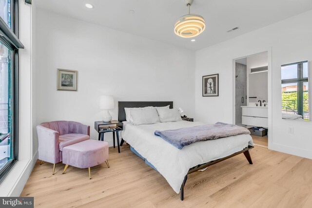 bedroom featuring ensuite bath and light hardwood / wood-style flooring