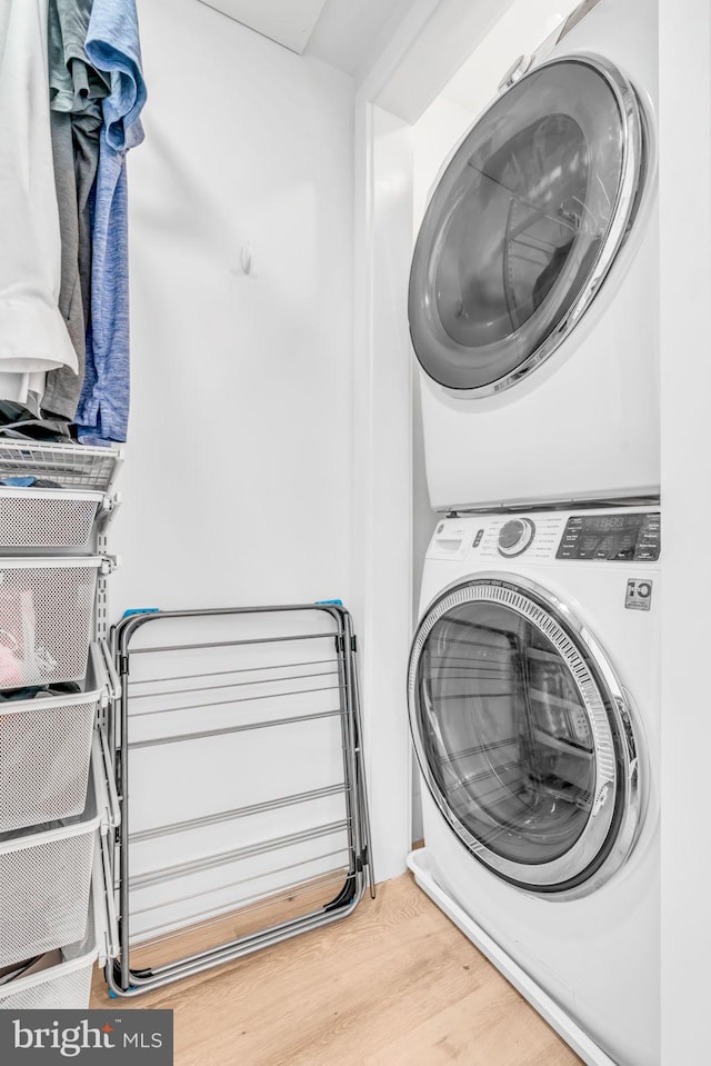 clothes washing area featuring stacked washing maching and dryer and hardwood / wood-style floors