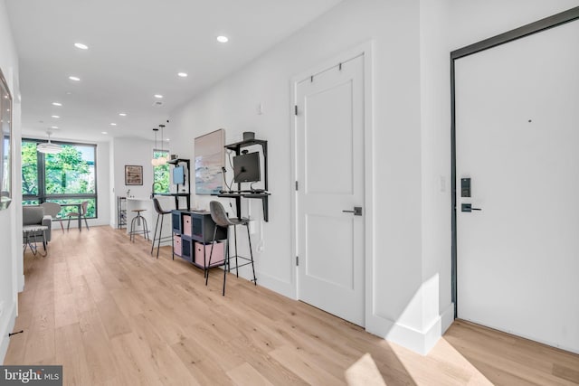 corridor with expansive windows and light hardwood / wood-style floors