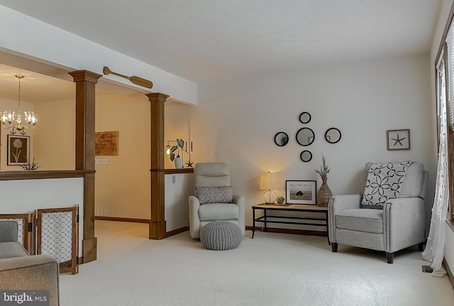 living area featuring ornate columns, carpet, and an inviting chandelier