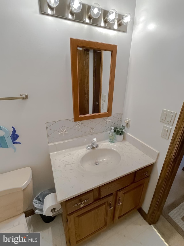 bathroom featuring toilet, vanity, and decorative backsplash