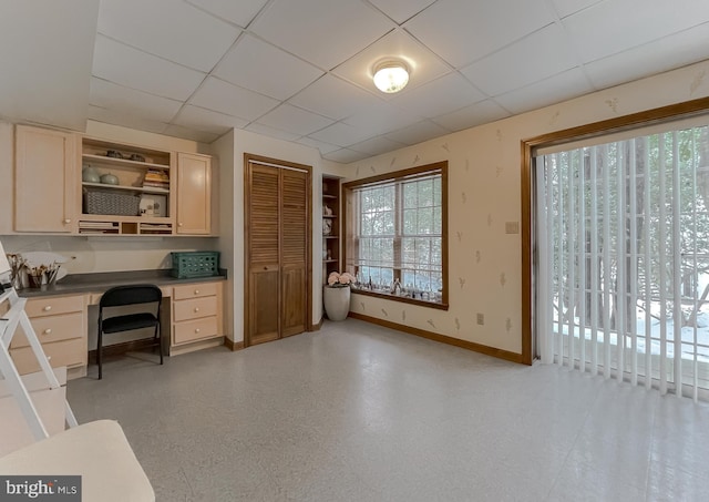 kitchen featuring light brown cabinetry, built in desk, and a drop ceiling