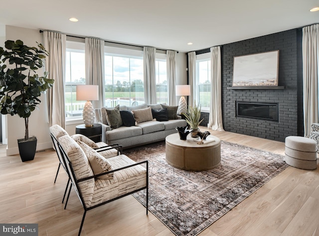 living room featuring a brick fireplace and light hardwood / wood-style flooring