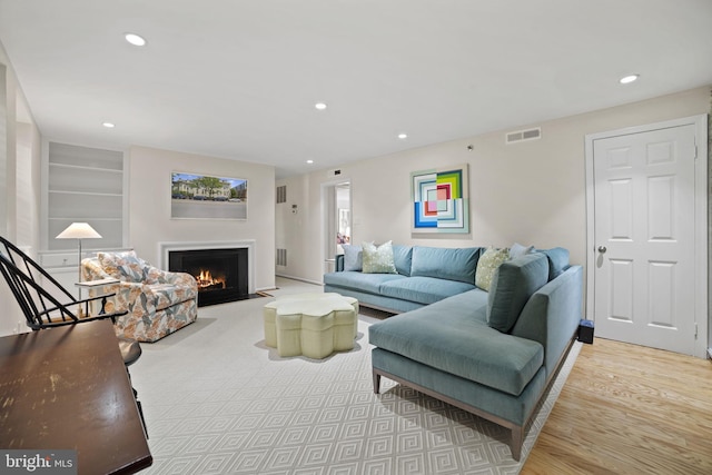 living room with built in features and light hardwood / wood-style flooring