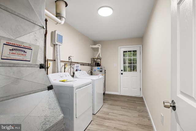 laundry room with water heater, light wood-style flooring, separate washer and dryer, laundry area, and baseboards