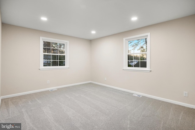 carpeted empty room with baseboards, visible vents, and recessed lighting