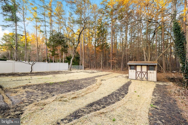 view of yard with fence, an outdoor structure, and a shed