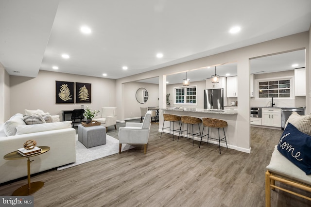 living area with light wood-type flooring, baseboards, and recessed lighting