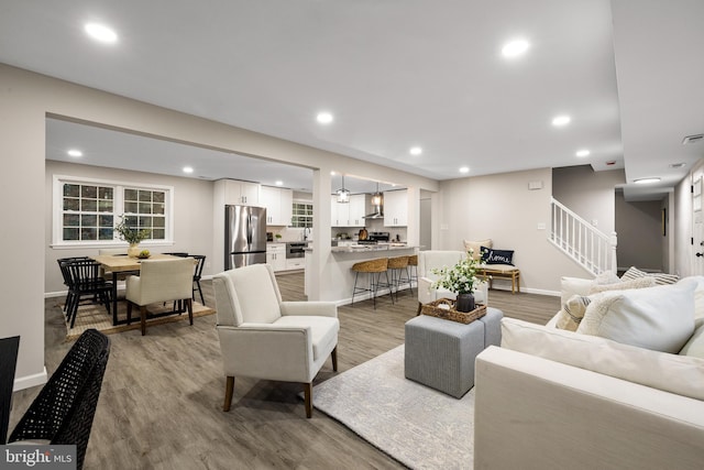 living room with light wood-style floors, stairway, and recessed lighting