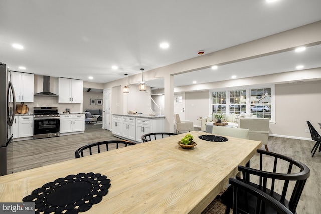 dining room featuring light wood finished floors, stairway, baseboards, and recessed lighting