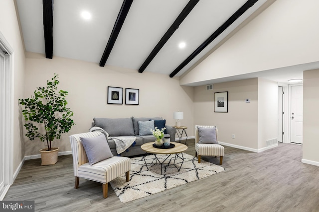 living room featuring beamed ceiling, wood finished floors, visible vents, and baseboards