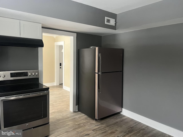 kitchen featuring under cabinet range hood, stainless steel appliances, wood finished floors, visible vents, and white cabinets