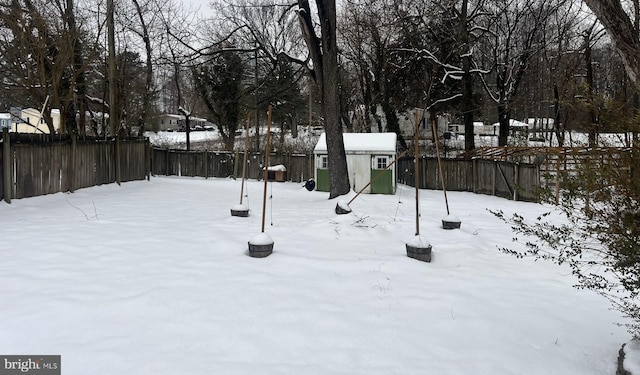 yard layered in snow featuring a storage unit and fence