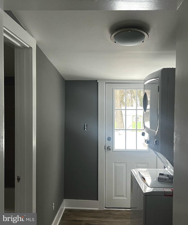 washroom with laundry area, dark wood-style flooring, stacked washing maching and dryer, and baseboards