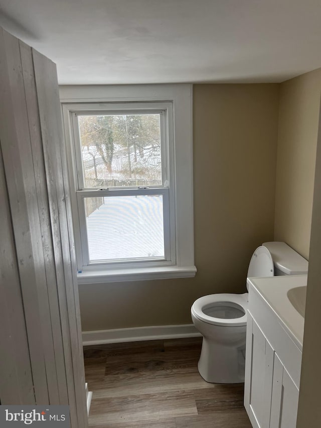 bathroom with toilet, baseboards, wood finished floors, and vanity