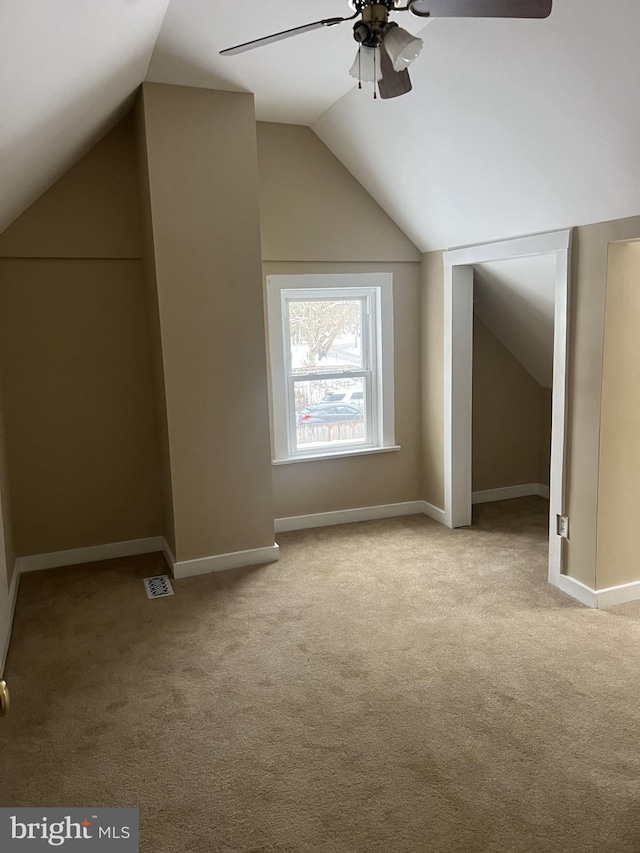 additional living space featuring light colored carpet, vaulted ceiling, baseboards, and ceiling fan