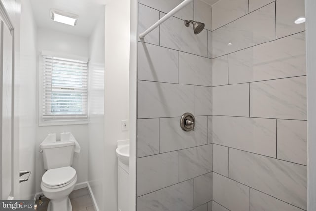 bathroom featuring vanity, a tile shower, and toilet