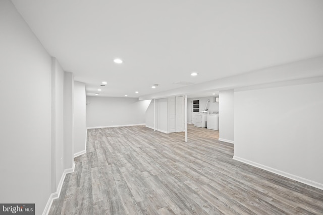 basement featuring independent washer and dryer and light hardwood / wood-style flooring