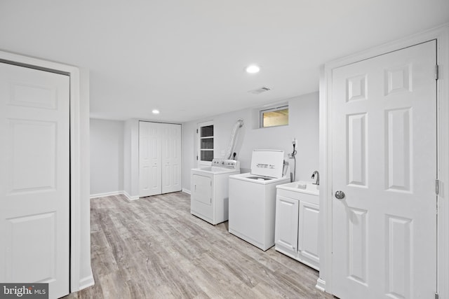 laundry area with cabinets, sink, independent washer and dryer, and light hardwood / wood-style flooring