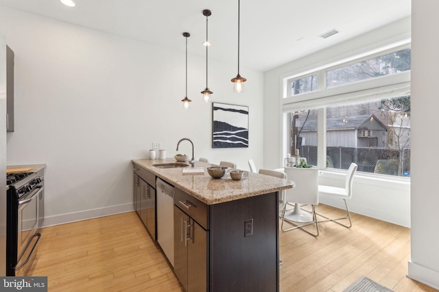 kitchen featuring light stone counters, decorative light fixtures, visible vents, appliances with stainless steel finishes, and a sink