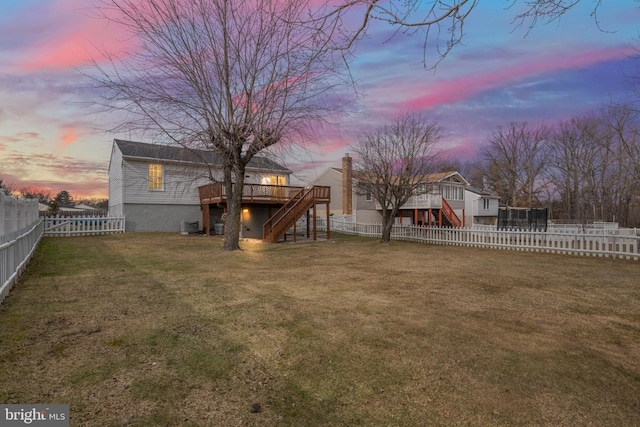 yard at dusk featuring a wooden deck