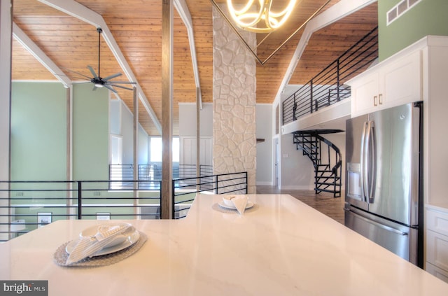 kitchen featuring wood ceiling, beamed ceiling, stainless steel fridge, and white cabinets