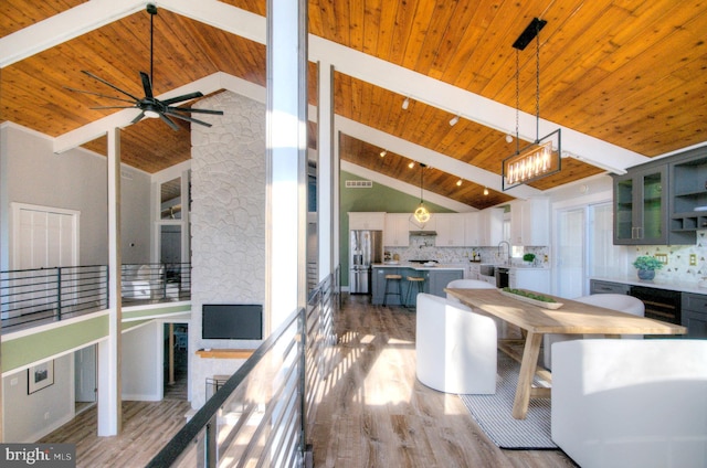 kitchen with stainless steel refrigerator with ice dispenser, decorative light fixtures, hardwood / wood-style floors, and a kitchen island