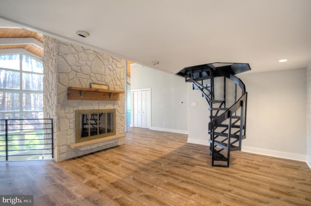 unfurnished living room featuring lofted ceiling, a fireplace, and wood-type flooring