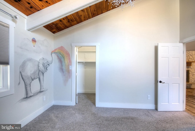 unfurnished bedroom with a walk in closet, vaulted ceiling with beams, light carpet, and wood ceiling