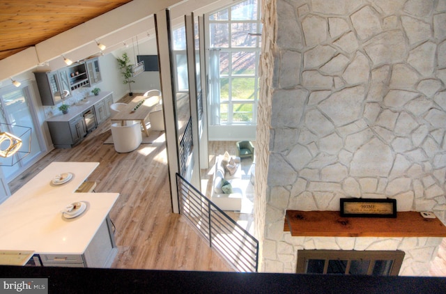 living room featuring light wood-type flooring, wooden ceiling, and a fireplace