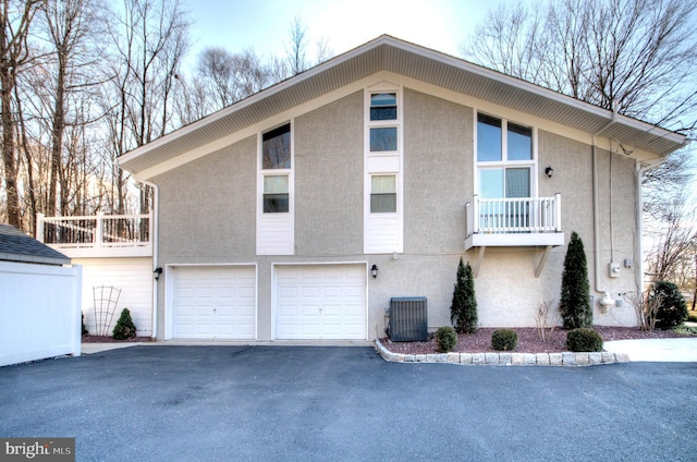 view of home's exterior with a balcony, a garage, and central AC unit