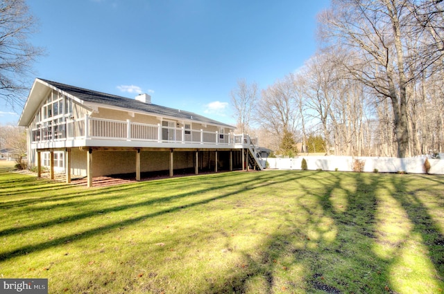 back of property with a sunroom, a yard, and a deck