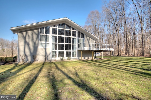 rear view of house featuring a wooden deck and a lawn